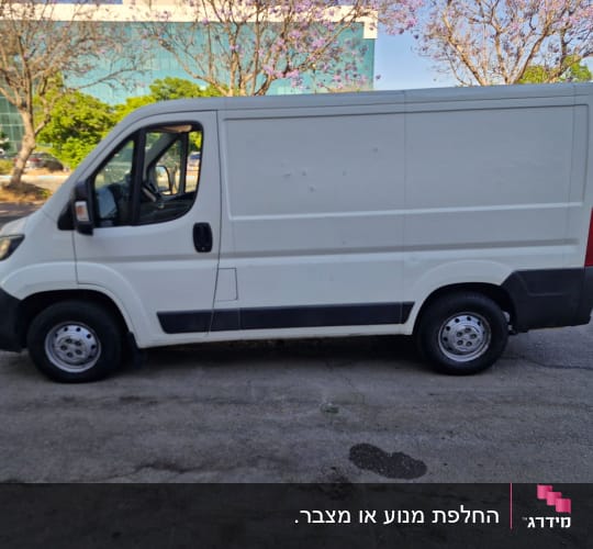 רכב מסחרי לבן חונה ברחוב ליד בניין